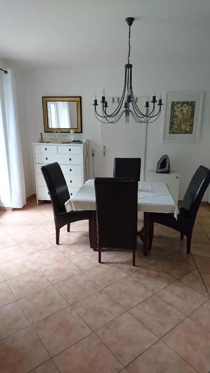 a dining room with a table and chairs and a chandelier at Olivades in Rehlingen-Siersburg