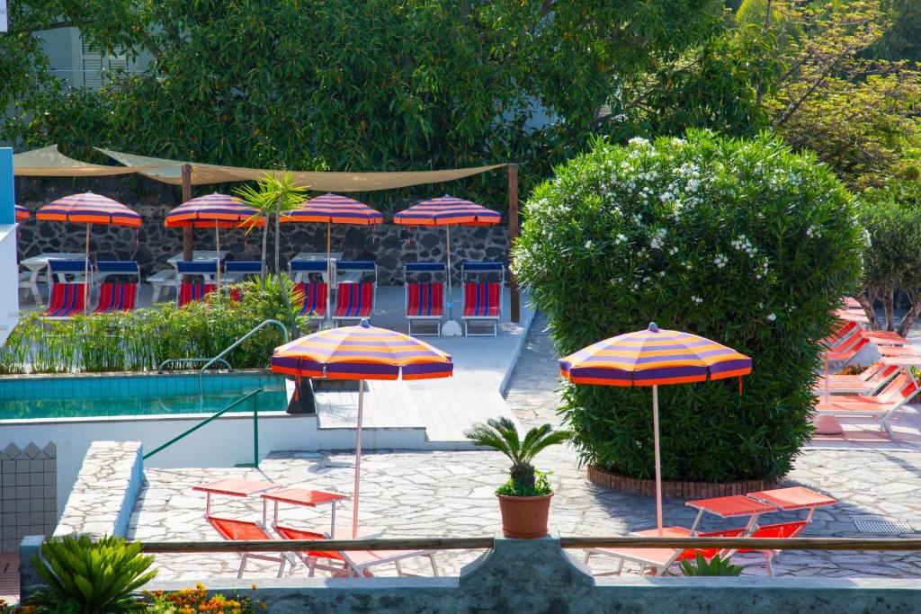 a patio with umbrellas and chairs and a pool at Hotel La Mandorla in Ischia