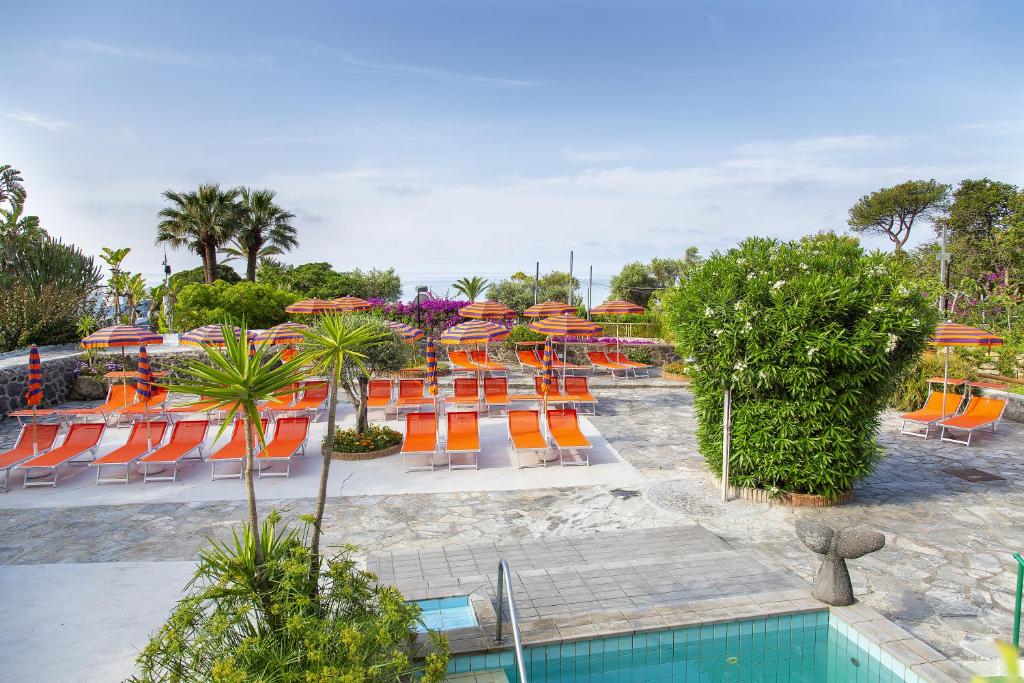 a resort with chairs and umbrellas and a pool at Hotel La Mandorla in Ischia