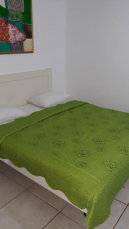 a green blanket laying on top of a bed at Pension Giulia in Timişoara