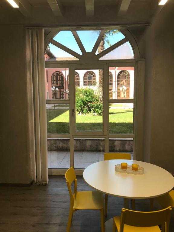 een tafel en stoelen in een kamer met een groot raam bij Vea Apartment in Padenghe sul Garda