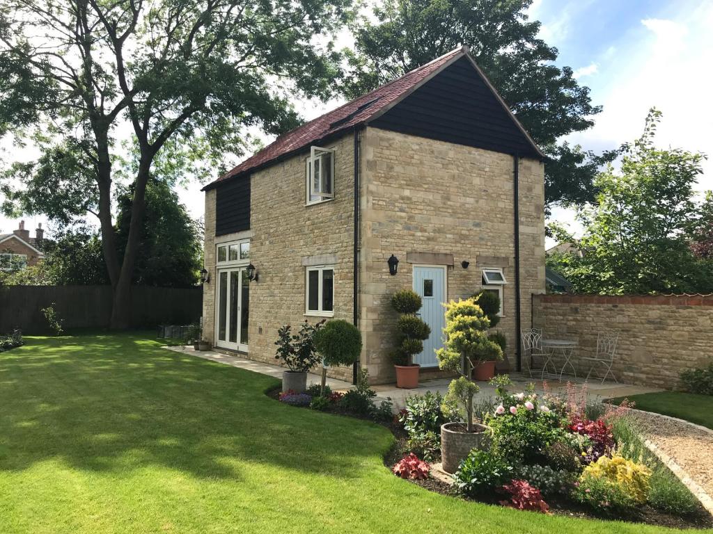 ein kleines Backsteinhaus mit einem Rasenhof in der Unterkunft The Old Barn 26 Church Street in Market Deeping