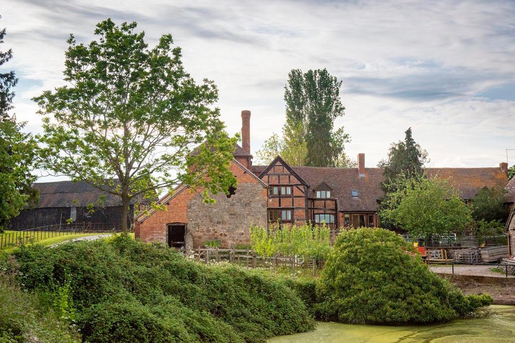 uma velha casa de tijolos com árvores em frente em Huntlands Farm Bed & Breakfast em Bromyard