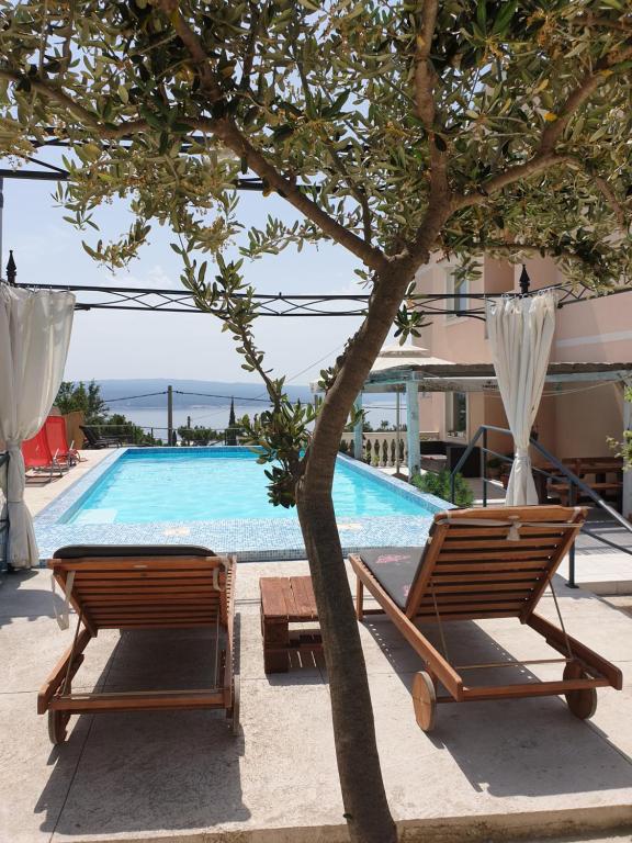 two chairs and a tree next to a swimming pool at Apartments Velic in Crikvenica