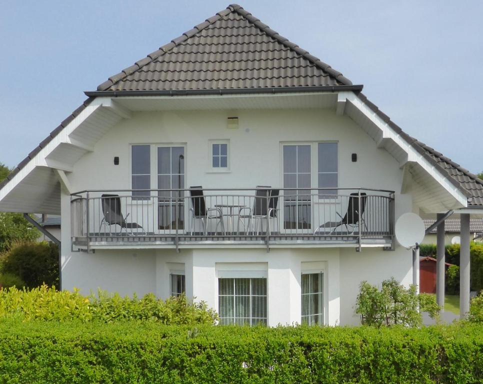 a white house with chairs on a balcony at Dom Max in Trzęsacz