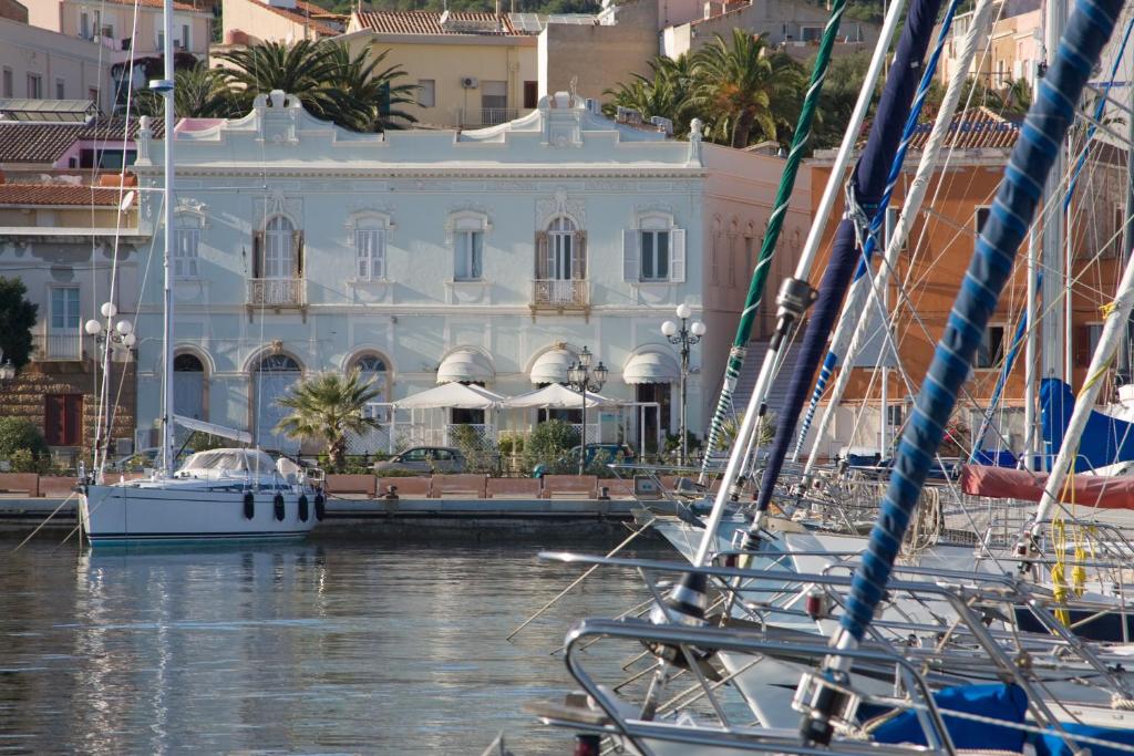 um grupo de barcos ancorados em frente a um edifício branco em Hotel Hieracon em Carloforte