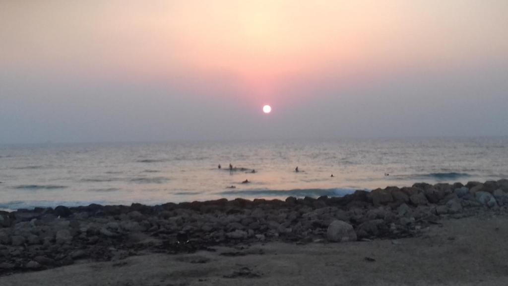 a sunset over the ocean with people in the water at Ashkelon a front of the sea in Ashqelon