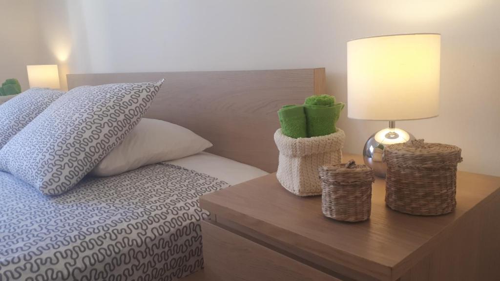 Schlafzimmer mit einem Bett und einem Tisch mit einer Lampe in der Unterkunft Corinthia Premium Apt - A Jewel next to the sea in Pyla