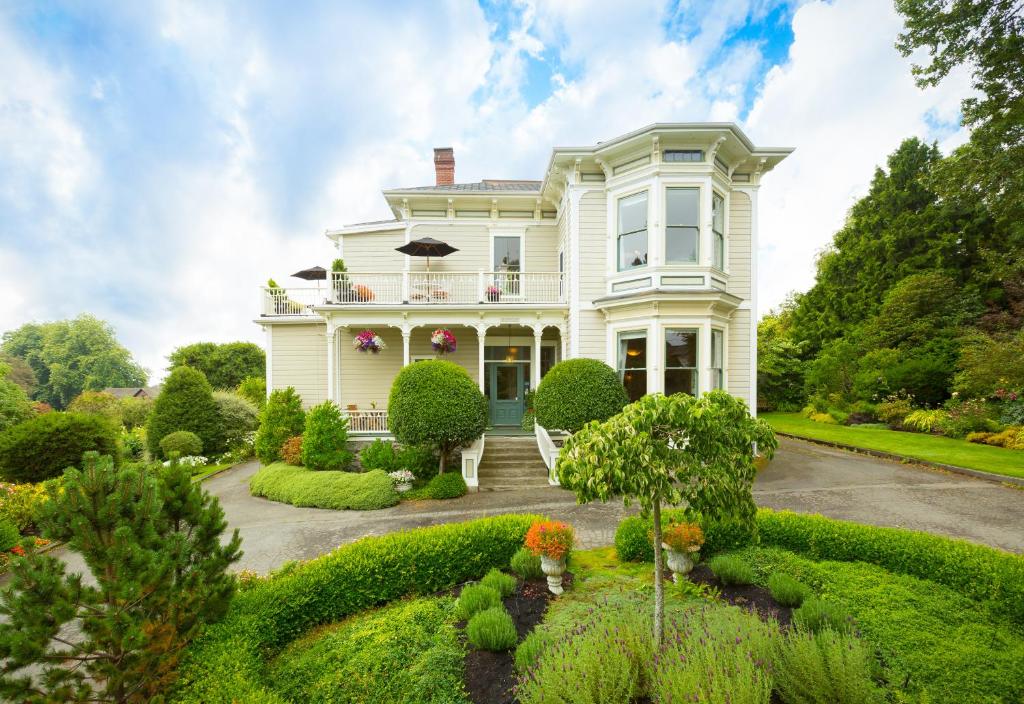 une grande maison blanche avec un jardin dans l'établissement Fairholme Manor Inn, à Victoria