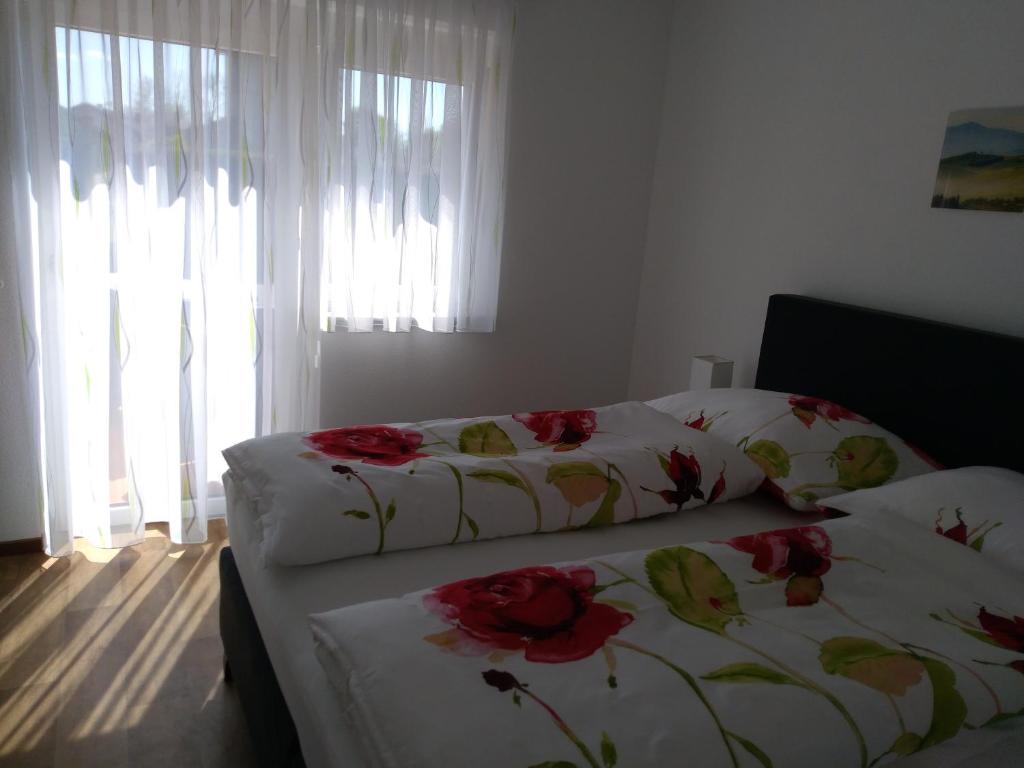 Dos camas en un dormitorio con flores rojas. en Ferienwohung Fam. Fink, en Riegersburg