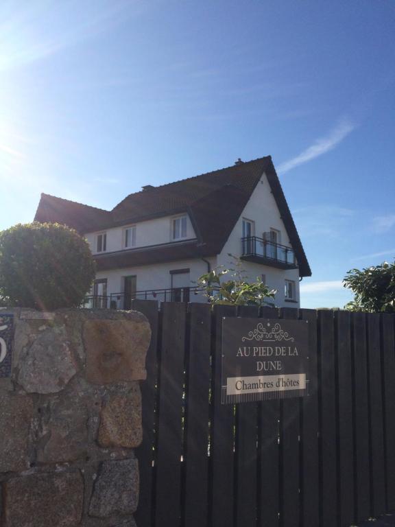 een huis achter een hek met een bord erop bij Au pied de la dune in Sangatte