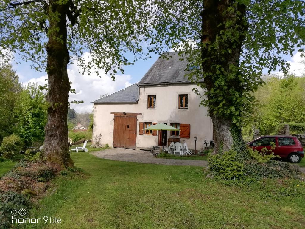 una casa bianca con due alberi davanti di Chambre d hôte le lavoir a Saint-Brisson