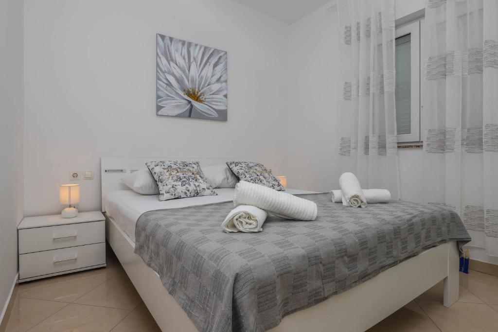 a white bedroom with a bed with two pillows at Apartments Ankica in Crikvenica