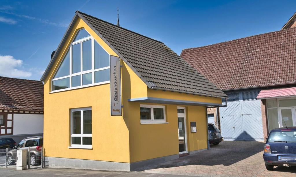 een geel huis met een zwart dak bij Gästehäuschen-Hösbach in Hösbach