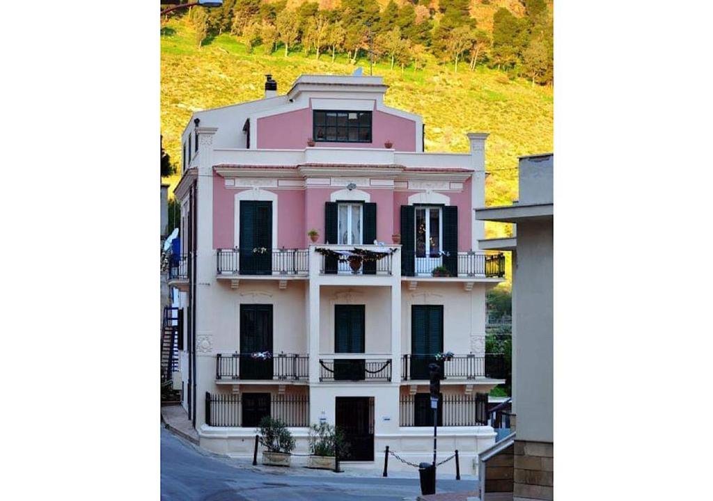 a pink house with a balcony on a hill at Liberty house in Castellammare del Golfo