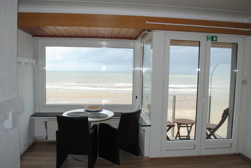 een eetkamer met een tafel en uitzicht op het strand bij De Zee in Oostende