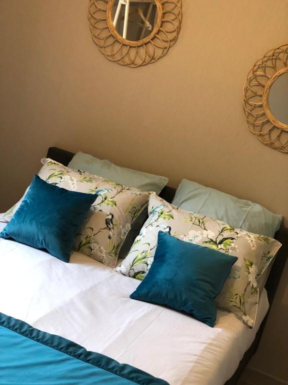 a bed with blue and white pillows on it at La petite maison des gîtes de Joséphine in Saint-Dyé-sur-Loire