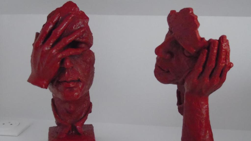 two red statues of two people holding their hands up at L'attrape coeurs in Mantilly