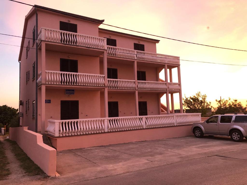 ein rosafarbenes Gebäude mit einem davor geparkt in der Unterkunft Apartments Bernarda 2 in Nin