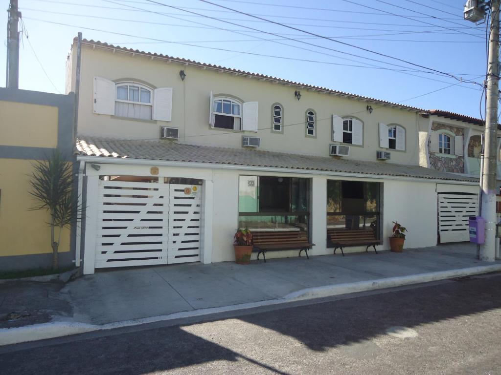 ein weißes Haus mit zwei Bänken davor in der Unterkunft Pousada Vida Boa in Cabo Frio