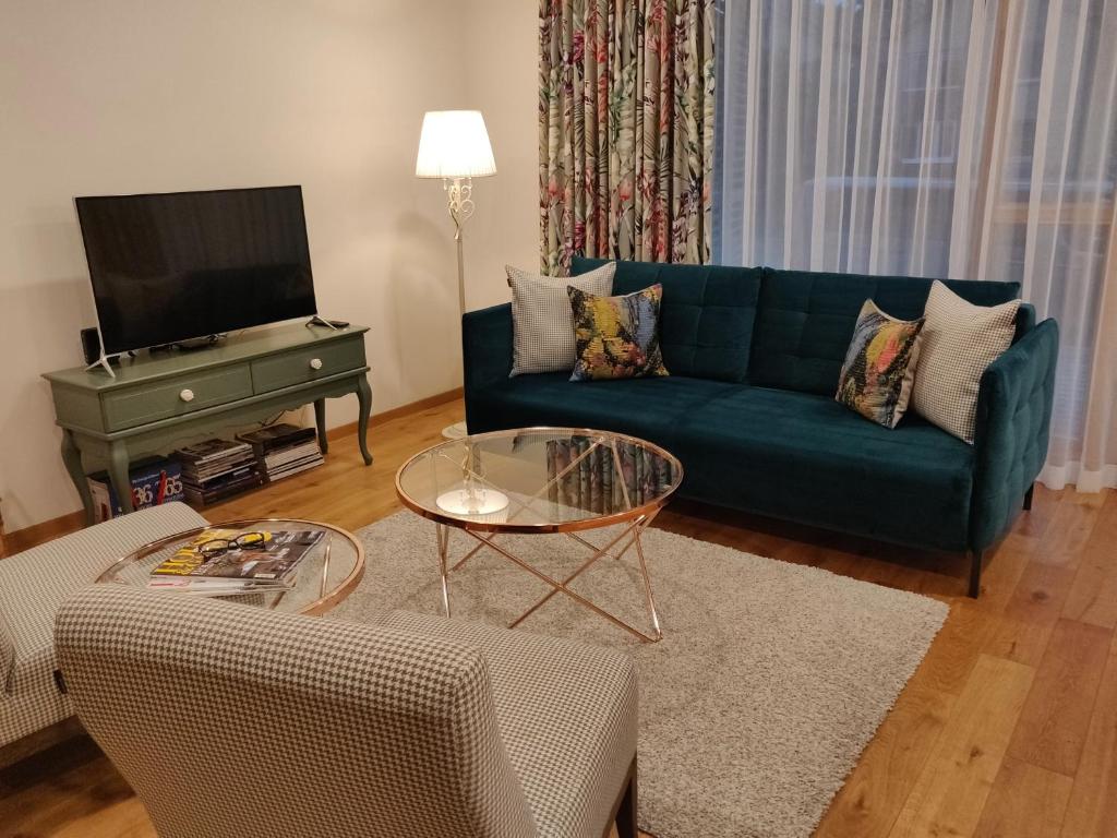 een woonkamer met een blauwe bank en een tv bij Kopu Vetrunges II - Nida Apartments in Nida