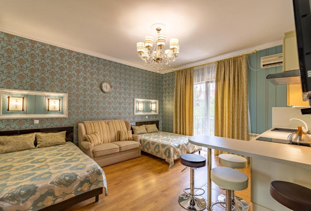 ゲレンジークにあるGuest House Domashniy Uyutのベッドとリビングルームが備わるホテルルームです。