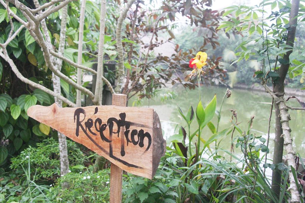 a wooden sign with graffiti on it in a garden at Thai Binh Garden in Thái Bình