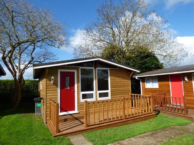 una pequeña casa de madera con puerta roja en Chalet 26, en Seaton