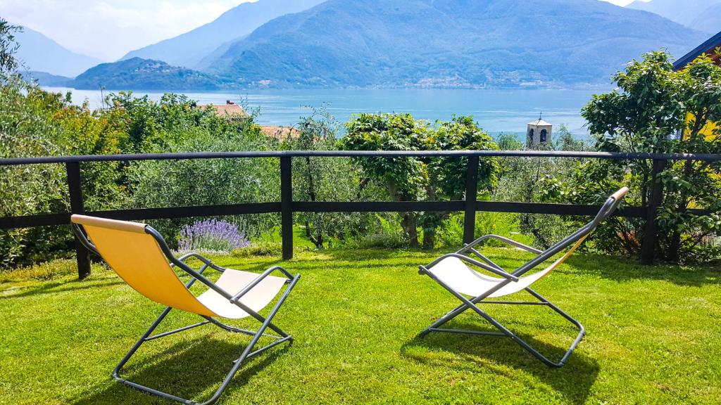 ムッソにあるAppartamenti Il Medeghinoの芝生の上に座って水辺を眺めることができる椅子2脚