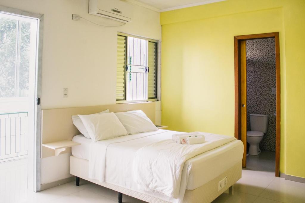 Cama blanca en habitación con baño en Hotel Guaíba, en Guaíba