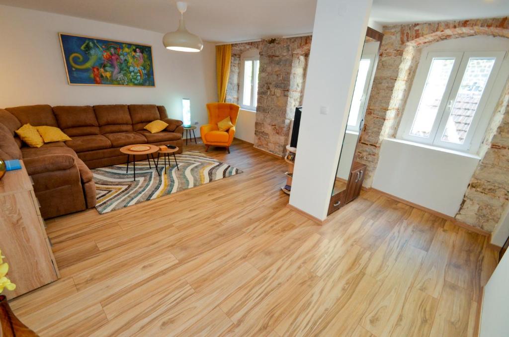ein Wohnzimmer mit einem braunen Sofa und Holzböden in der Unterkunft Portobello Old Town in Kotor
