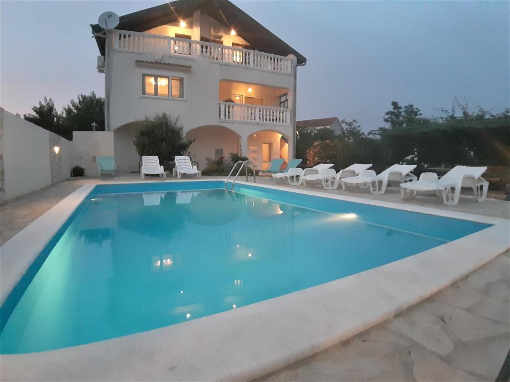 eine Villa mit einem Pool vor einem Haus in der Unterkunft Apartments"Nika" with private pool in Galovac