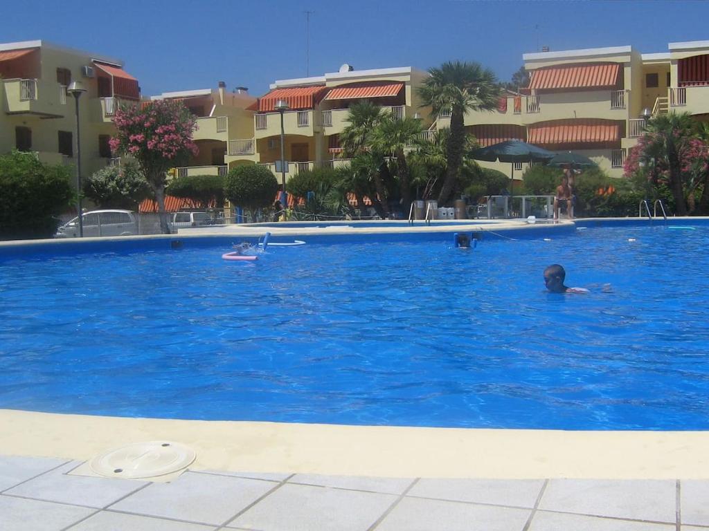 a person swimming in a large blue swimming pool at APPARTAMENTO LIDO 1 in Alghero