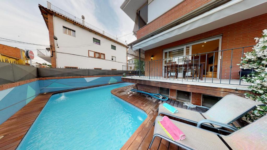 una piscina con 2 tumbonas y una casa en HOUSE OF JOY , CASA EN BANYOLES, en Banyoles