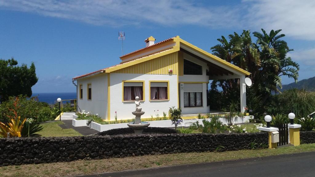 a small yellow house with a fountain in front of it at Casa do Costa in Fajã
