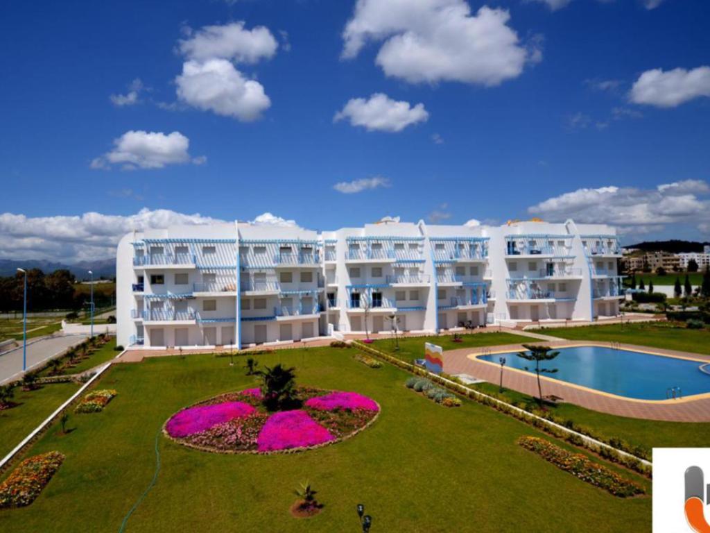 un grande condominio con un grande giardino e una piscina di Beautiful apartment at RIVIERA BEACH RESIDENCE CABO NEGRO a Cabo Negro
