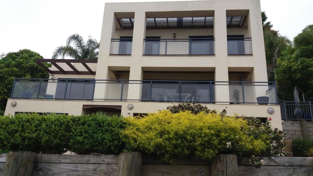 a white building with a balcony in front of it at Harbour Views Omokoroa in Omokoroa Beach