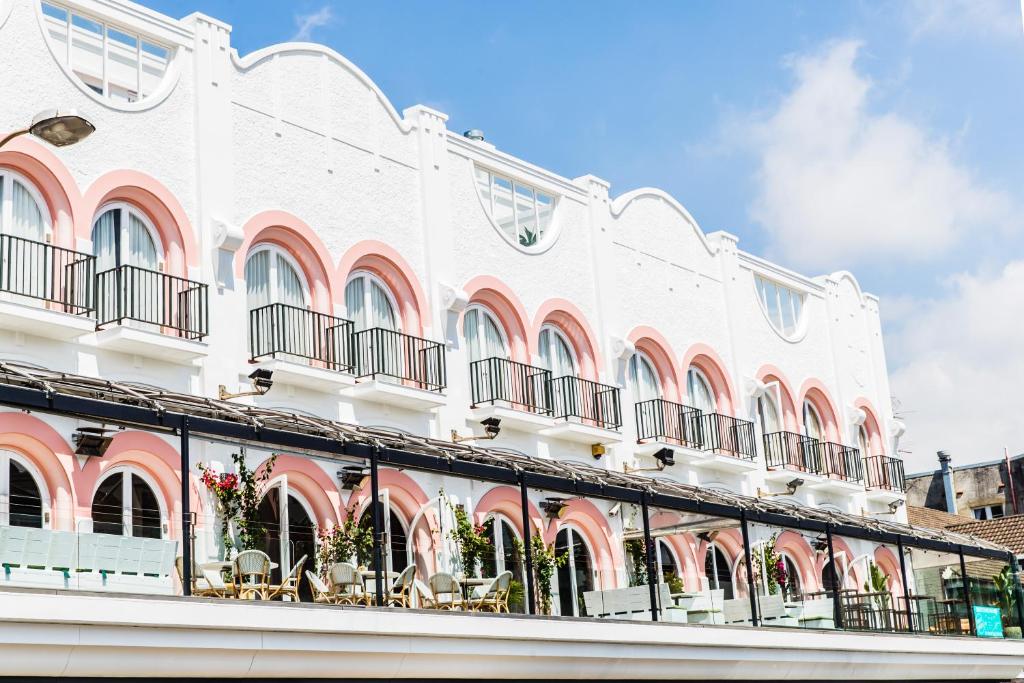 a white building with balconies and tables and chairs at Hotel Ravesis in Sydney