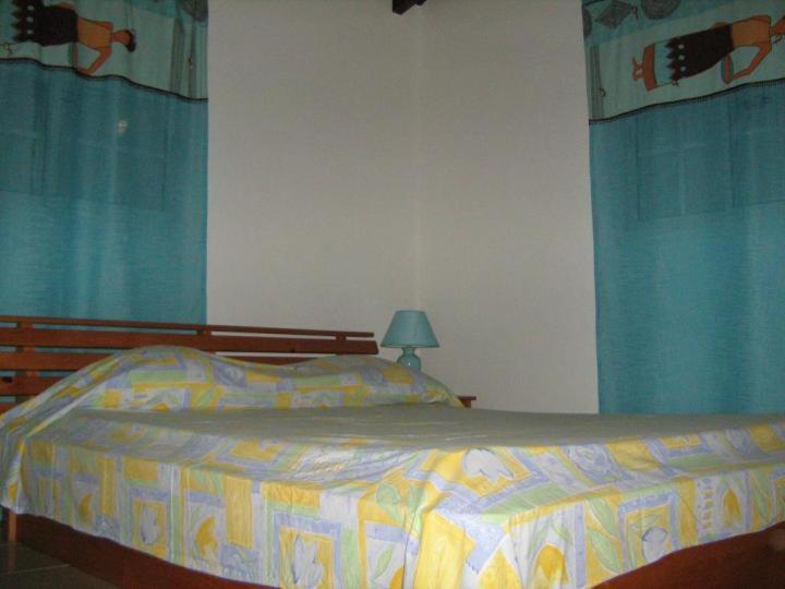 a bedroom with a bed with blue curtains at Villa Josiane in Sainte-Anne