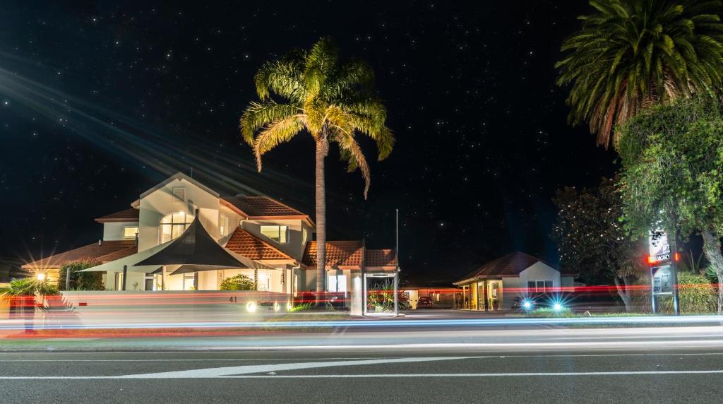 a palm tree in front of a house at night at Pacific Coast Motor Lodge in Whakatane