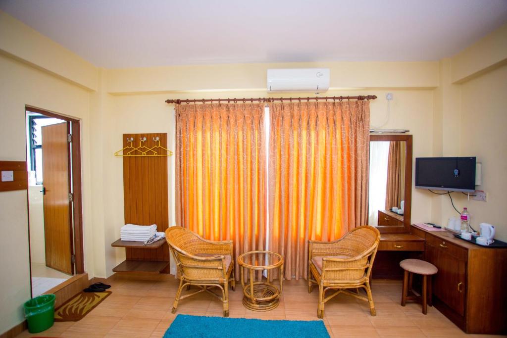 Zimmer mit Stühlen, einem Schreibtisch und einem TV in der Unterkunft Hotel Tara in Pokhara