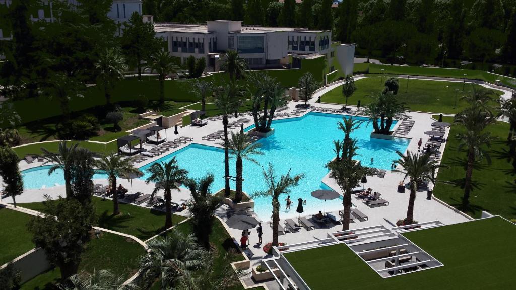 a beach with a pool, lawn chairs, and trees at Ergife Palace Hotel in Rome