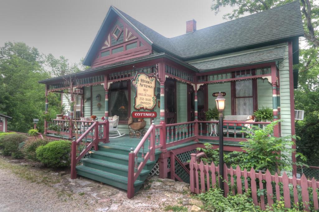 a red and green house with a porch at Hidden Springs Bed and Breakfast in Eureka Springs