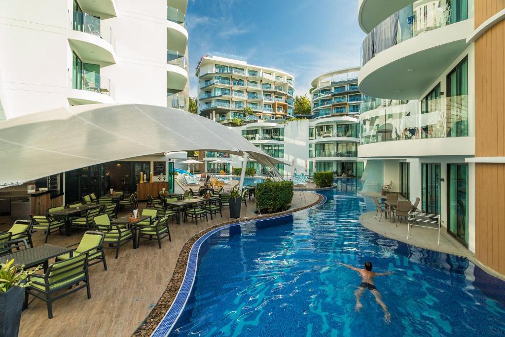 a person swimming in a swimming pool in a building at Absolute Twin Sands by Lofty in Patong Beach