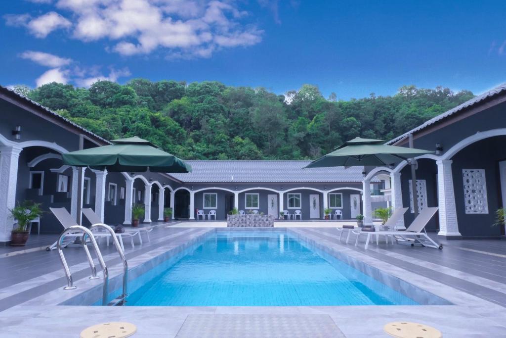 una piscina con sillas y sombrillas junto a un edificio en Cenang Rooms With Pool by Virgo Star Resort en Pantai Cenang