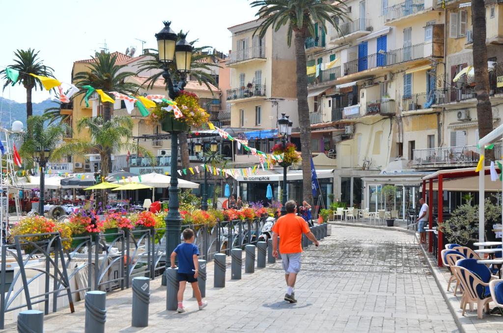 a man and a boy walking down a city street at Hôtel Méditerranée in Calvi