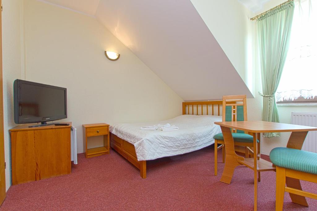 a bedroom with a bed and a tv and a table at Willa Marianna in Jastrzębia Góra