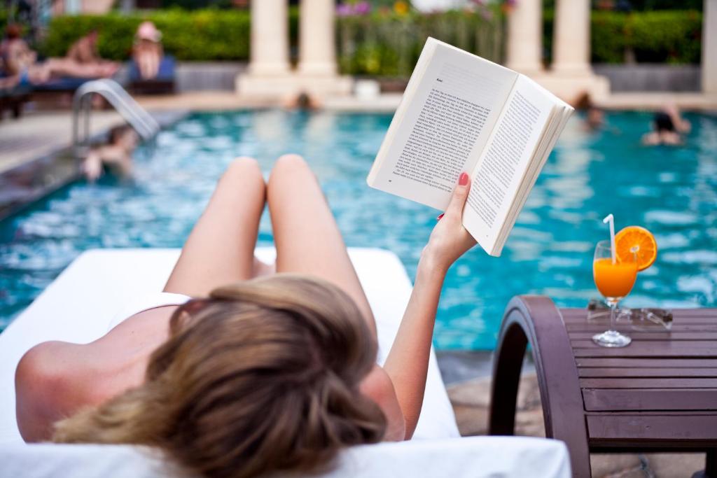 una mujer tumbada en una piscina leyendo un libro en Lantana Pattaya - SHA Extra Plus, en Norte de Pattaya