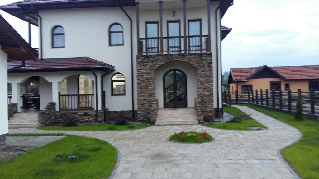 a large white house with a stone driveway at Agropensiunea Izana in Drăguţeşti