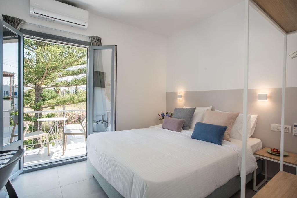 a bedroom with a large white bed and a balcony at Nautilus Apartments-Suites in Parikia